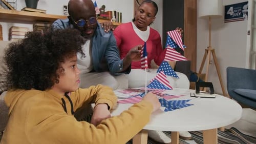 Family Assembling American Flags Indoors for Holiday
