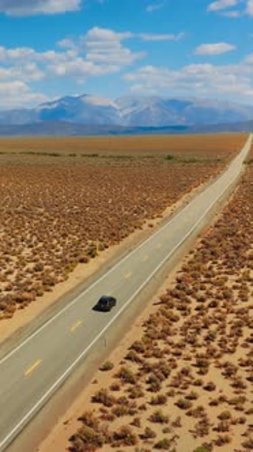 Following the black cars riding by the empty road through the deserted land. Highway from California