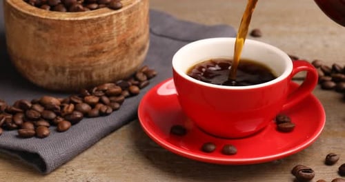 Pouring Hot Coffee in a Cup with Beans