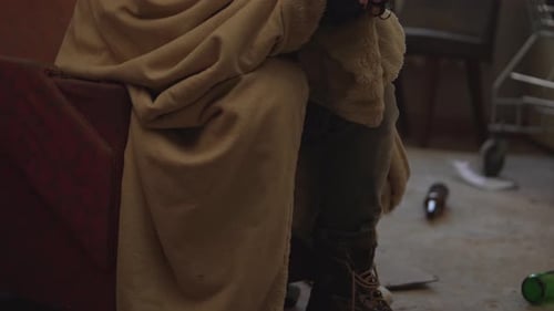 Boom Shot Homeless Poor Man Covered in a Blanket Sitting in a Room of an Abandoned Building Filled