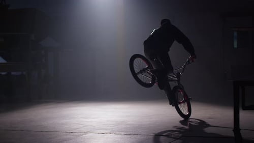 Bmx rider performs extreme stunts in dark urban warehouse shot on red epic