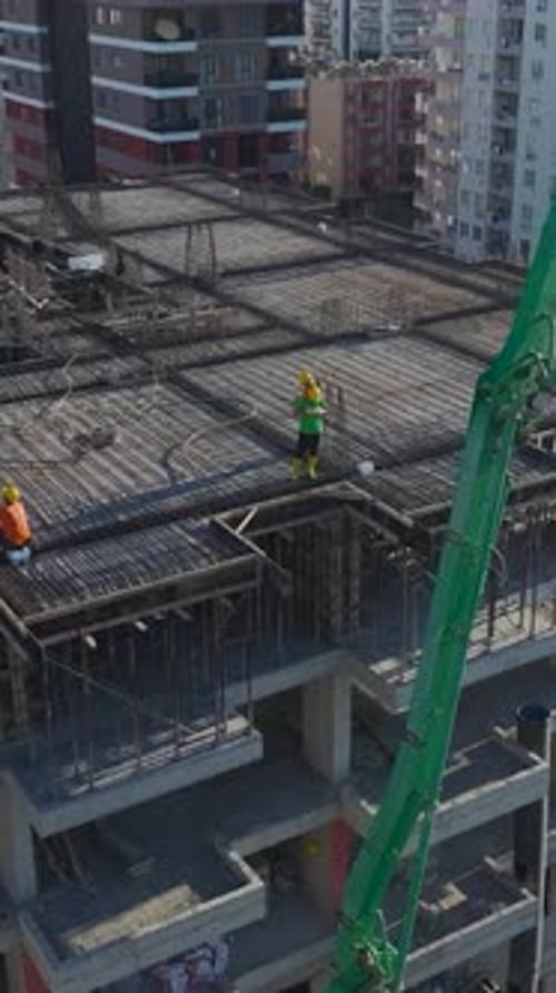 Vertical Video of Workers Laying Foundations While a Crane Lifts Beams on a Residential Construction
