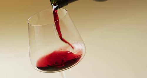 Vinho tinto derramado em copo sobre fundo amarelo com espaço de cópia