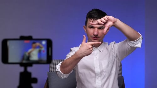 Blogger Man Takes a Blog on the Phone and Shows a Frame Frame Gesture