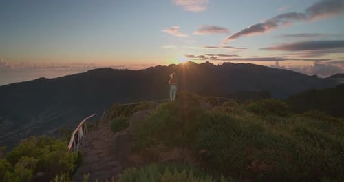 Fit hiking woman in sportswear staring at dreamy sunrise on mountain top