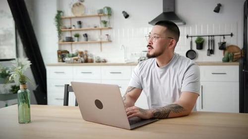 Man Working on Laptop in Bright Modern Kitchen