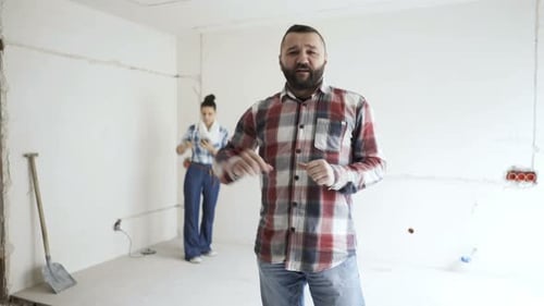 Pareja en su nueva casa, hombre hablando de un proyecto y mujer trabajando en él