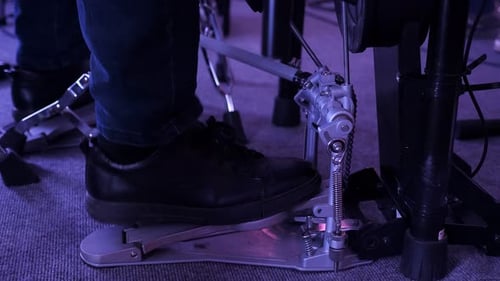 Closeup of a Drummer's Foot Playing on a Bass Drum Pedal in a Dark Room
