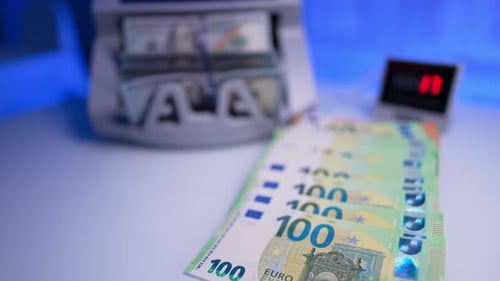 One hundred euro banknotes are laid on the desk. Cash counting device works calculating dollars.