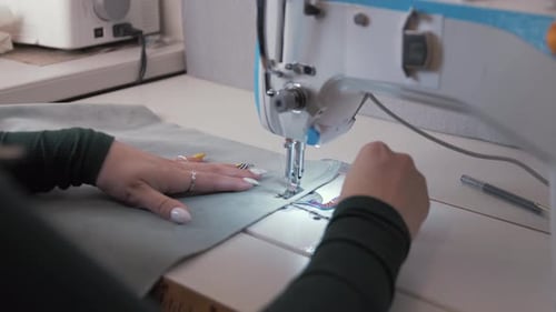 Seamstress Sewing Gray Fabric on Sewing Machine