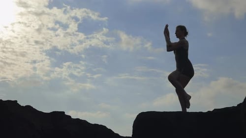 Woman Doing Yoga on Rocky Beach at Sunset