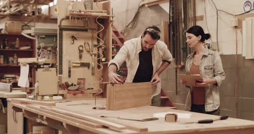 Two young carpenters working together inside a carpentry shop