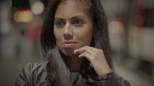 Linda jovem olhando para as pessoas que viajam na cidade à noite
