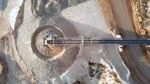 Aerial view of a large Quarry during work hours with Stone sorting conveyor belts and an open pit