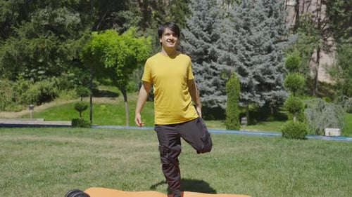 Man Stretches on Exercise Mat in Green Park