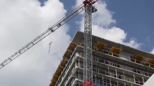 Tilt down shot of a apartament's building under works with a big crane.