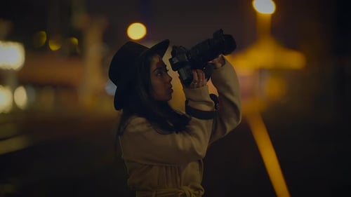 Young Woman Taking Pictures at Night in City