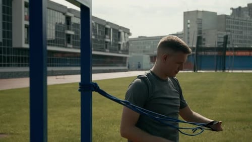 Sportler mit Acheiria trainiert mit Widerstandsbändern im Stadion