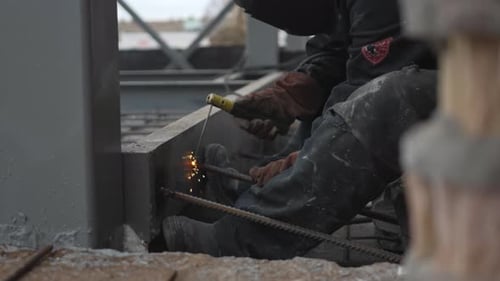 Construction Worker Welding Rebar on Building Framework