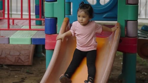 happy toddler baby girl sliding and playing at outdoor playground