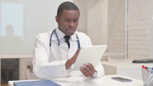 African Doctor Browsing Internet on Tablet in Hospital