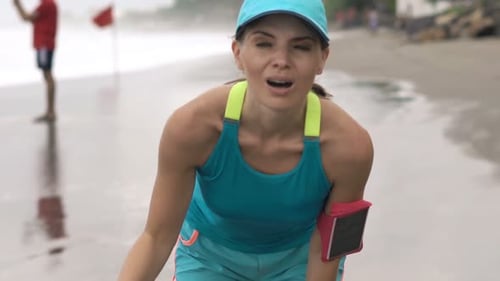 Tired young woman resting after jogging on a beautiful beach during her vacations