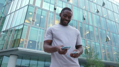 African American Man Holding Money Dollar Bills on Urban Street in City Businessman Guy Counting