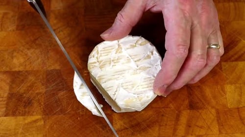 Beginning to Slice a Block of Camembert Cheese