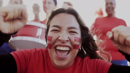 Aficionado al deporte latino celebrando con un equipo público con fondo de estadio. La gente aplaude al campeón de fútbol