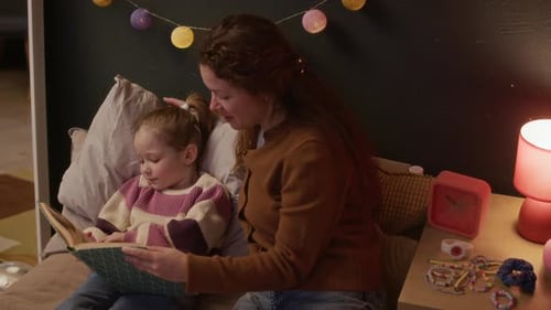Woman Reads Book to Child at Bedtime
