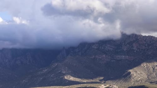 Les nuages d'orage s'accumulent et recouvrent le sommet des montagnes alors que la caméra se déplace lentement vers la droite.