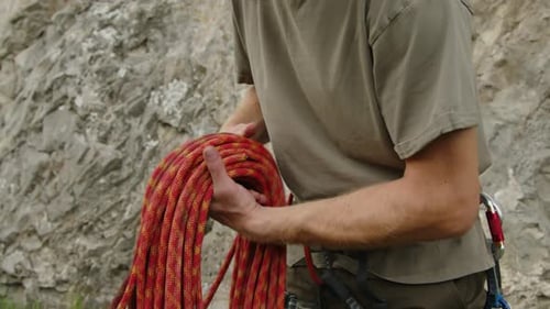 Mountain Climber Preparing Rope for Rock Climbing