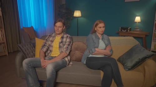 A Married Couple Sits on the Couch Turning Their Backs to Each Other A Man and a Woman are Offended