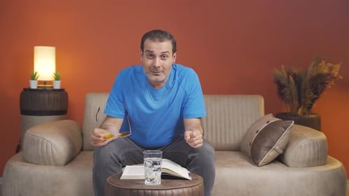 Man Sits on Couch, Gestures and Talks to Camera