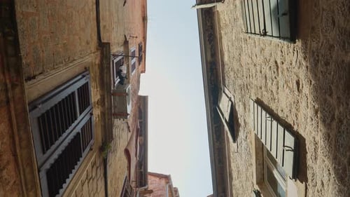 View from the ground on old narrow street with stone buildings and tiled roofs at old European city.