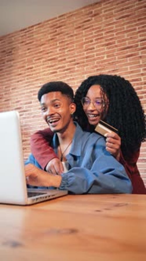Vertical African American Couple is Using a Laptop to Search a Sale on a Online Shop Excited Husband