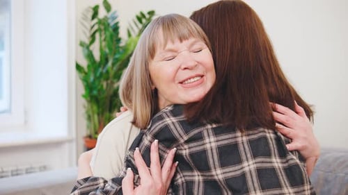 Affectionate woman embracing mother, showing love in home