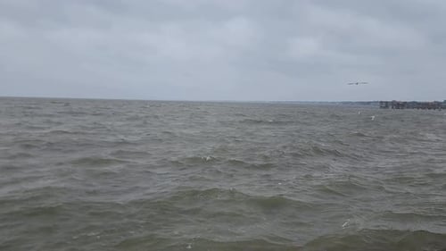 This is a video of a large ocean bay with rough waves during an afternoon storm.