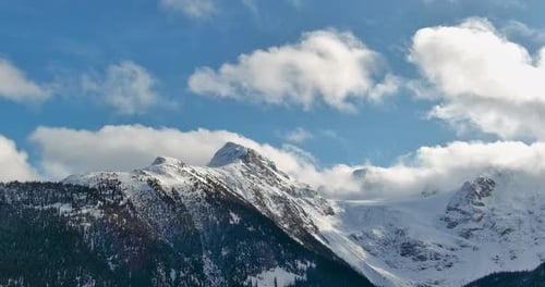 Scenic Snowy Mountain Landscape and Trees. Blue sky and fluffy clouds. Aerial view. British Columbia