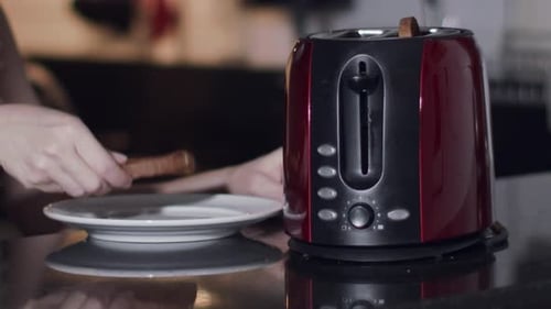 Person Making Toast in a Red Toaster