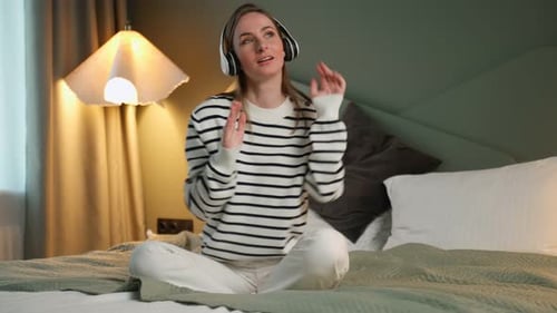 Woman Enjoying Music with Headphones on Bed