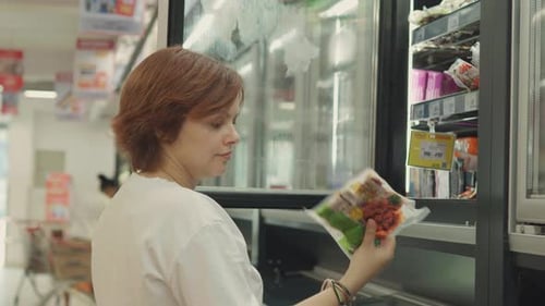 Young Woman Choosing Frozen Food in the Supermarket Close Up