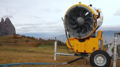 Snow cannon fan spins freely in the wind out of season in the Alpine mountains in Italy