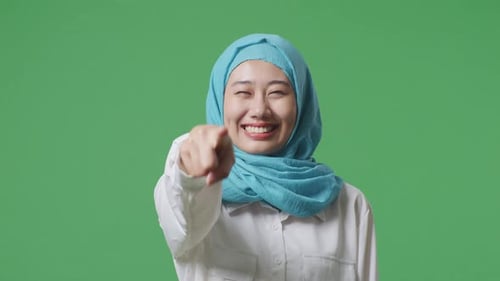 Close Up Of Asian Muslim Woman Smiling And Touching His Chest Then Pointing In The Green Screen