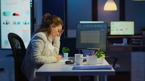 Woman Working on Computer in Dark Office at Night