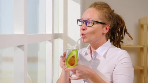 Portrait d'une femme boit une cure de désintoxication à l'avocat dans un bocal en verre au travail