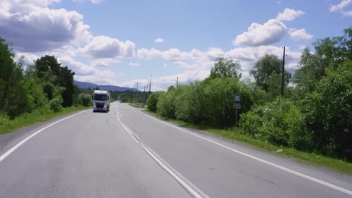 Truck Driving on Rural Highway Under Blue Sky