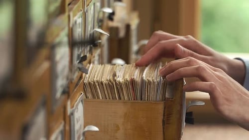 Female Student Studies in Library Using Card Catalog to Find Information and Research Material