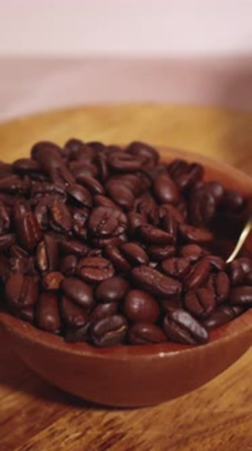 Coffee beans in bowl being scooped by spoon Slow Motion