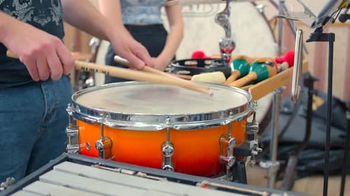 Escena de calentamiento de percusión, representación íntima de un músico ajustando el agarre durante una animada práctica en